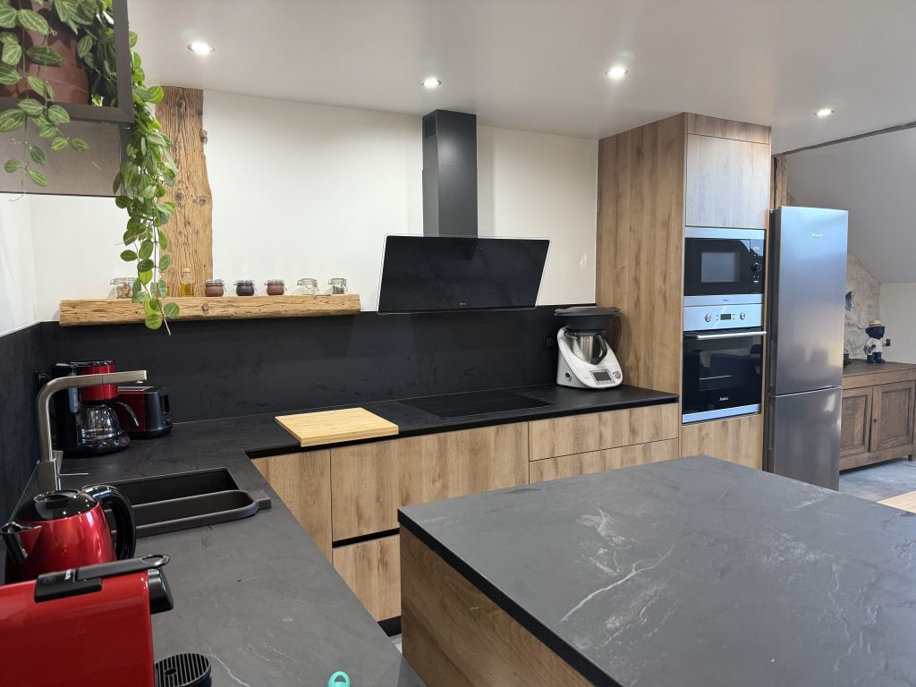 Cuisine moderne équipée du gîte Duclos de Lorme avec électroménager encastré, plan de travail noir et meubles en bois, Doubs.