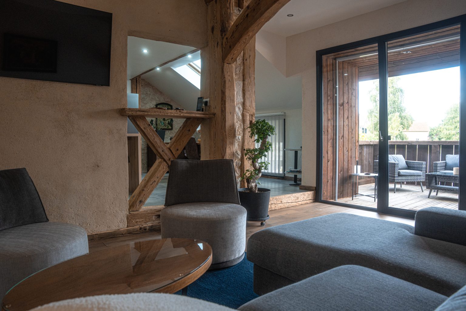 Salon lumineux du Gîte du Clos de l'Orme, avec canapé confortable, décoration moderne et vue sur le balcon